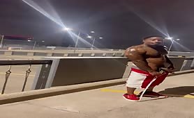 Muscular black exhibitionist masturbates on a bridge